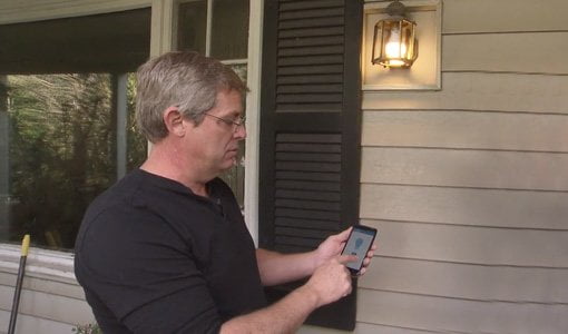 Allen Lyle usa un teléfono inteligente para controlar la luz del porche.
