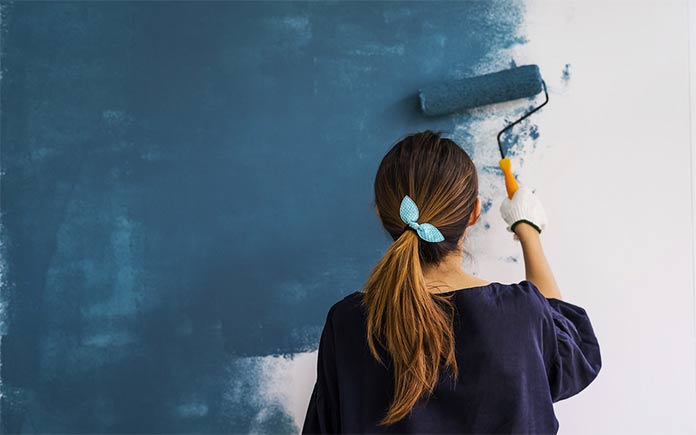 Mujer joven pintando una pared azul