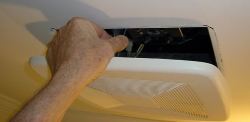 Presionando los clips de resorte para quitar la cubierta del ventilador de ventilación.