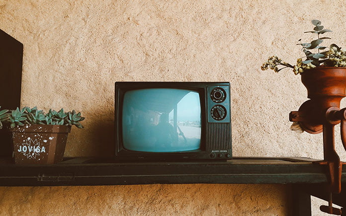 Televisión de 1960 en un estante en una sala de estar con papel tapiz anticuado