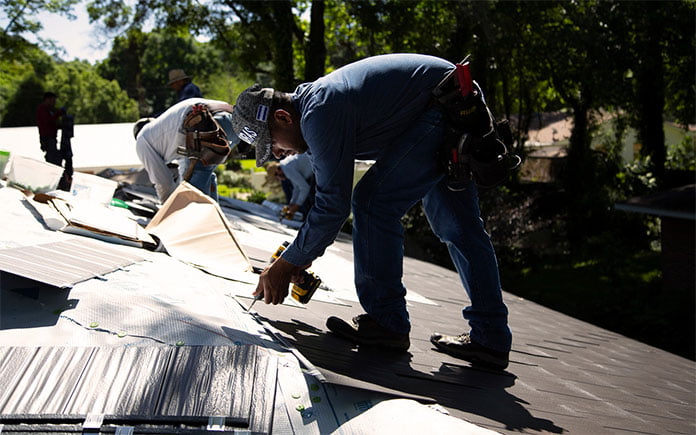 Los trabajadores instalan nuevos techos de metal sobre tejas de asfalto